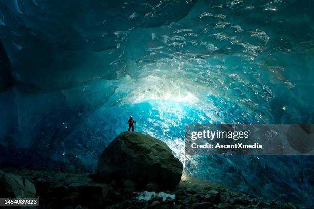 man inside a glacial ice cave - explorer stock pictures, royalty-free photos & images