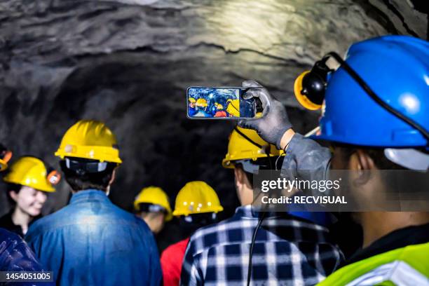 group of miners taking photos with a cell phone in a subway mine. - miner stock pictures, royalty-free photos & images