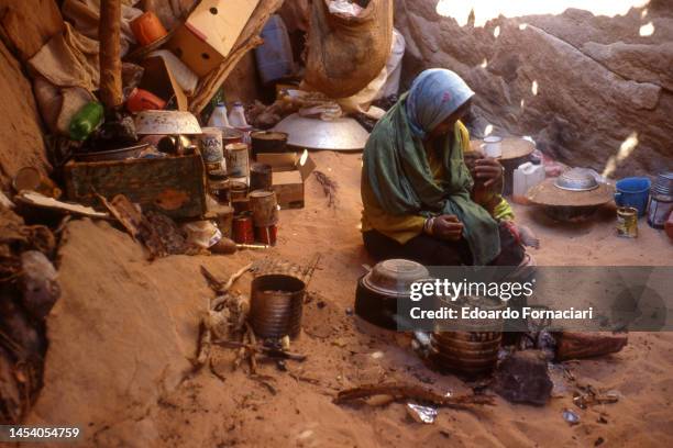 View of a woman as she holds a young child beside a stove in a Tuareg camp, Libya, March 16, 2002.