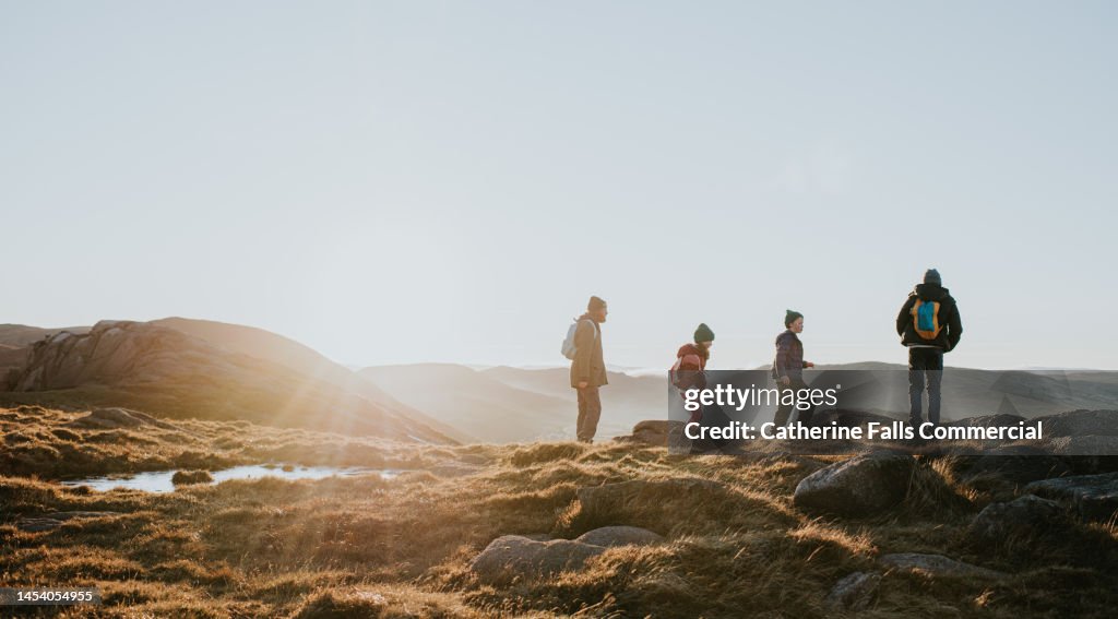 A young family enjoy the view from the top of a mountain
