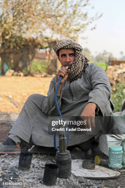 An Egyptian farmer smokes hookah in the Egyptian countryside on January 3, 2023 in Giza, Egypt.