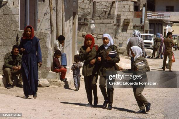 View of pedestrians, including three students, in an UNRWA camp for Palestinian refugees, Khan Dannun, Syria, March 19, 1988.