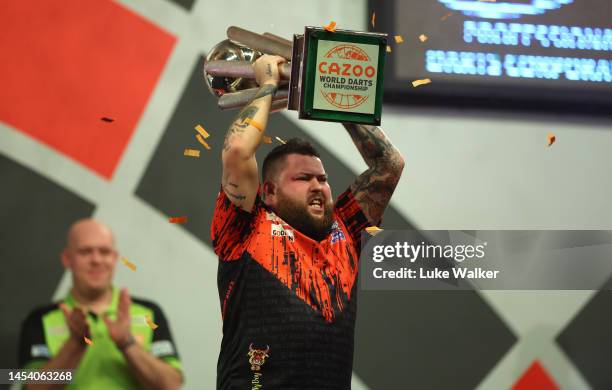 Michael Smith of England celebrates with the Trophy during the Finals against Michael van Gerwen of Netherlands during Day Fourteen of the Cazoo...