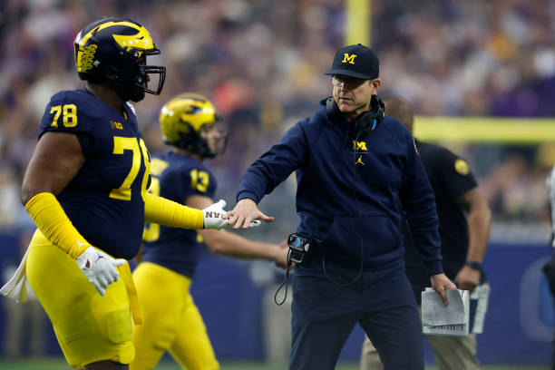 Head coach Jim Harbaugh of the Michigan Wolverines shakes hands with players during the first half of the Vrbo Fiesta Bowl against the TCU Horned...