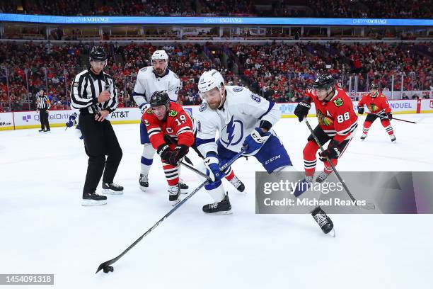 Jonathan Toews of the Chicago Blackhawks and Erik Cernak of the Tampa Bay Lightning battle for control of the puck during the second period at United...