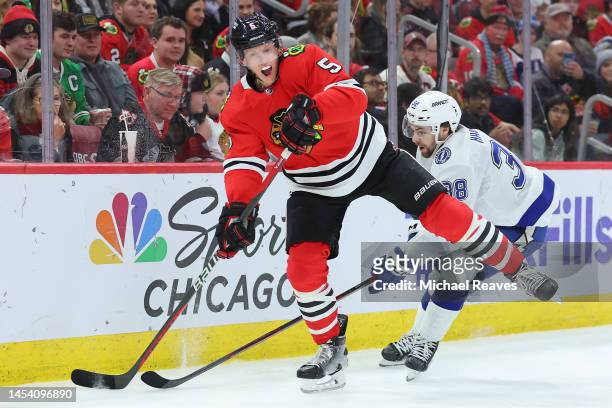 Connor Murphy of the Chicago Blackhawks passes around Brandon Hagel of the Tampa Bay Lightning during the third period at United Center on January...