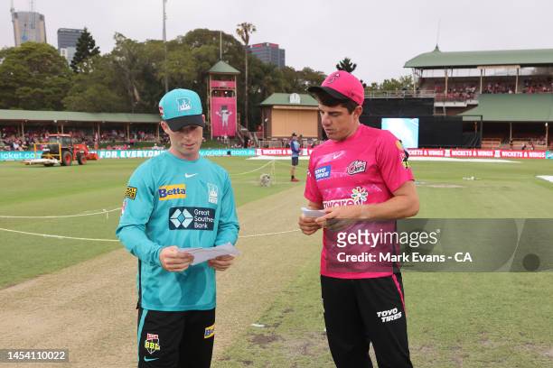 Moises Henriques of the Sixers swaps team lists with Jimmy Peirson of the Heat ahead of the Men's Big Bash League match between the Sydney Sixers and...