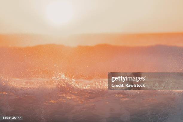 waves breaking on the shore at sunset - coral coloured stock pictures, royalty-free photos & images