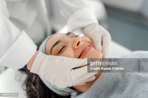 happy woman receiving a beauty treatment - protective face mask bildbanksfoton och bilder