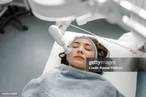 happy woman receiving a beauty treatment - clinic stockfoto's en -beelden