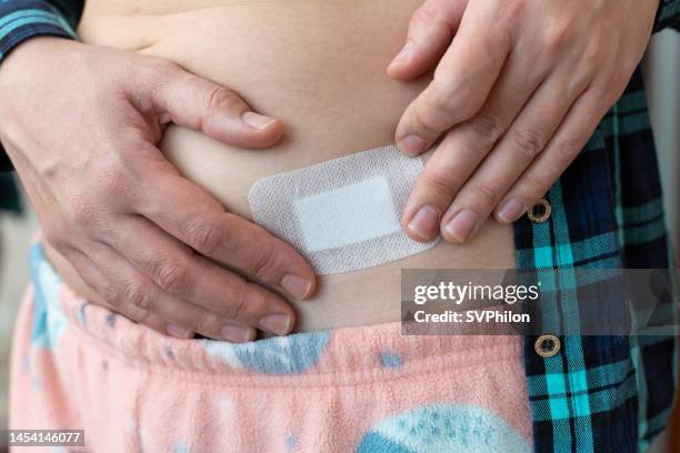 the woman applies one hrt patch onto the skin below the waist. - oestrogen stock pictures, royalty-free photos & images