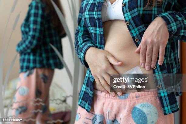 la mujer aplica un parche de trh sobre la piel debajo de la cintura. - progesterone fotografías e imágenes de stock