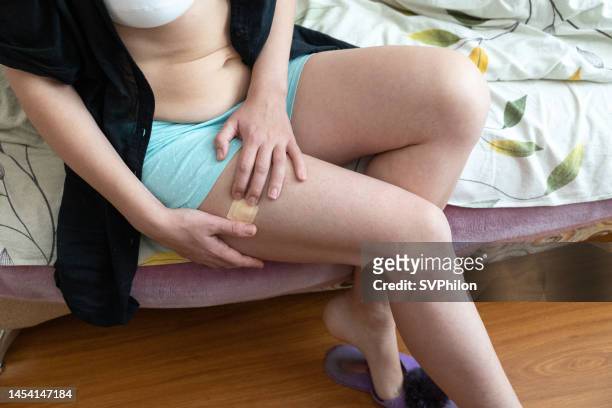 the woman applies one hrt patch to the skin of her upper thigh. - oestrogen stock pictures, royalty-free photos & images