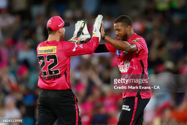 Chris Jordan of the Sixers celebrates the wicket of James Bazley of the Heat with Josh Philippe during the Men's Big Bash League match between the...
