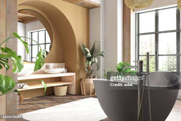 gemütliches badezimmer im boho-stil mit einer badewanne, pflanzen und gartenblick - deko bad stock-fotos und bilder
