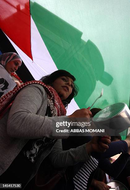 The Palestinian flag flies over protestors banging on pots during a demonstration in the West Bank city of Ramallah on May 29, 2012 in support of...