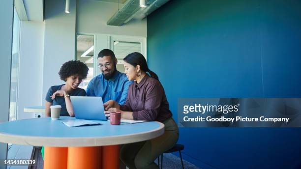 jóvenes empresarios sonrientes trabajando juntos en una computadora portátil en una oficina - mixed fotografías e imágenes de stock