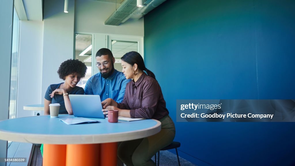 Smiling young businesspeople working together on a laptop in an office