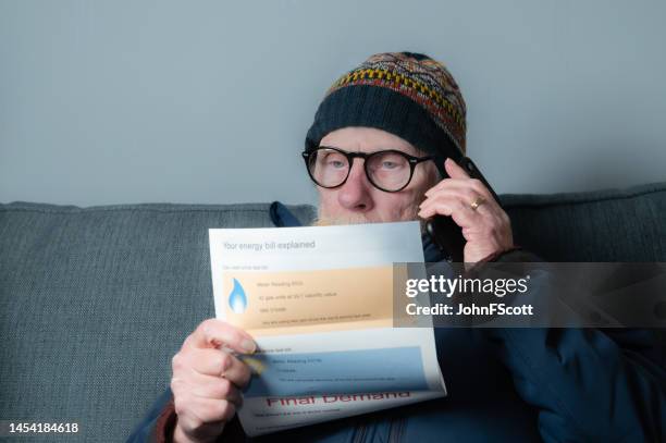 senior man using a phone while looking at a bill - energy bill stock pictures, royalty-free photos & images