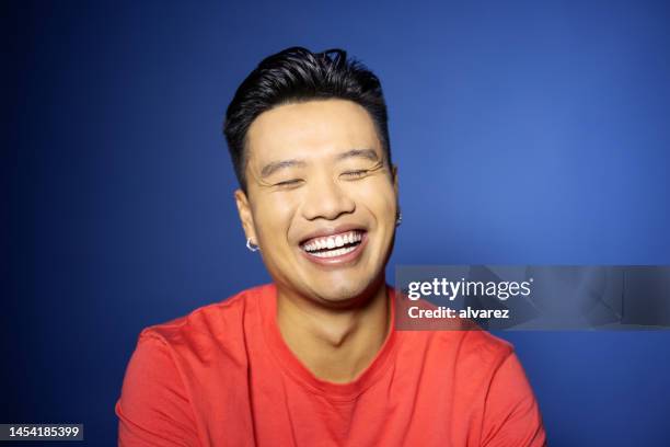 close-up portrait of smiling young vietnamese man on blue background - vietnamese ethnicity stock pictures, royalty-free photos & images