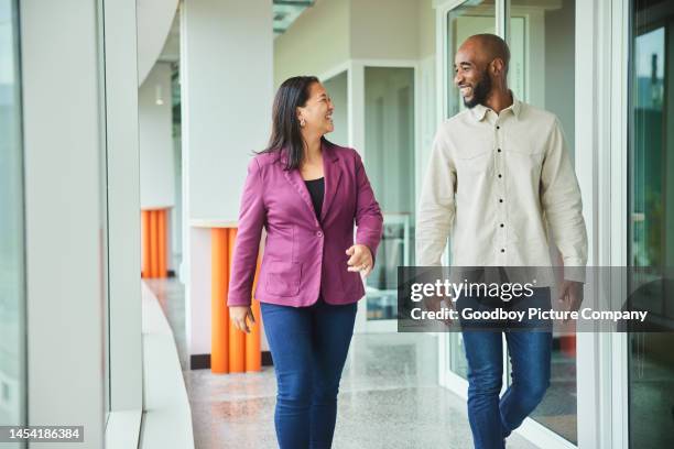 diverse businesspeople talking and laughing while walking in an office hall - corporate modern office bright diverse imagens e fotografias de stock