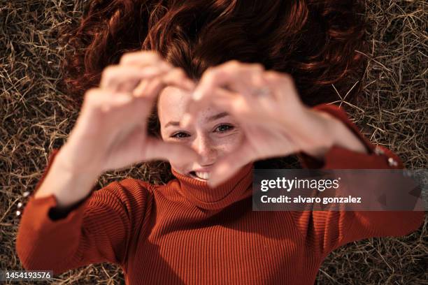 woman gesturing the shape of a heart with hands outdoors - gratitude stockfoto's en -beelden