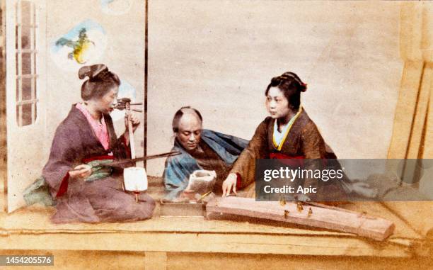 Japanese musicians playing the shamisen and the koto. Hand-tinted albumen photograph, c1880s.