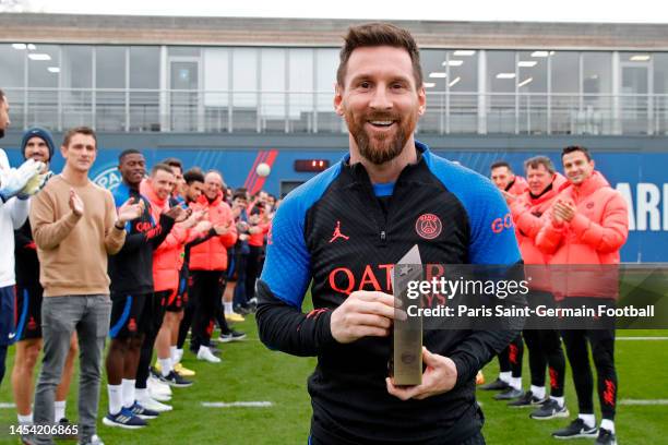 Leo Messi poses with a trophy and is congratulated by teammates and staff as he returns to a Paris Saint-Germain training after his World Cup title...