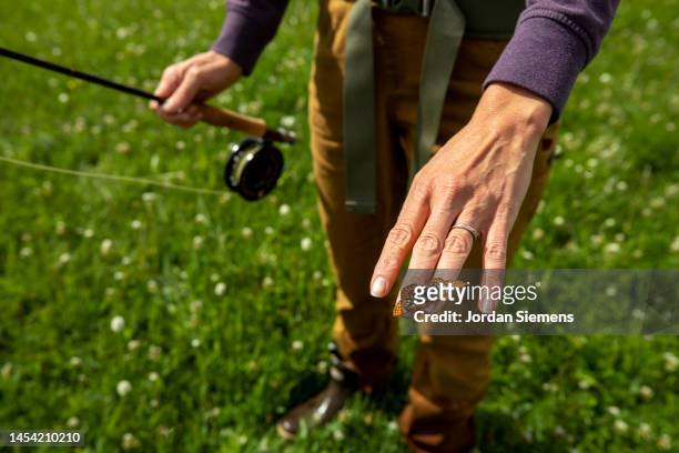 a butterfly lands on a womans hand while fishing. - dillon montana stock pictures, royalty-free photos & images