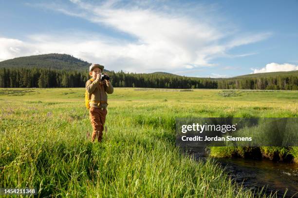 a young boy looking through binoculars. - meadow brook imagens e fotografias de stock