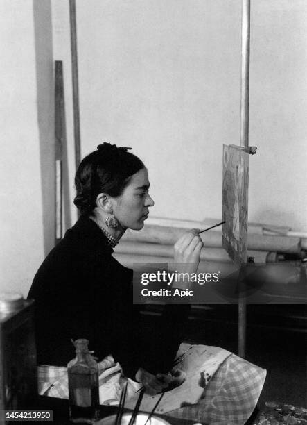 Frida Kahlo mexican painter, here painting a Self-portrait on the border line between Mexico and United States in Detroit Institute of Art mural...