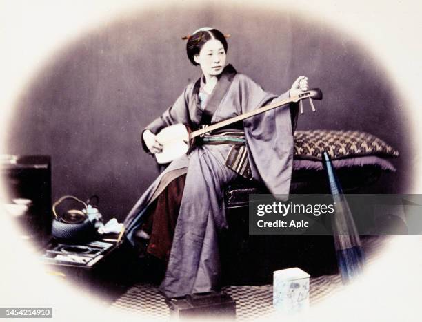 Japanese girl playing shamisen. Hand-tinted albumen photograph by Beato, c1860s..