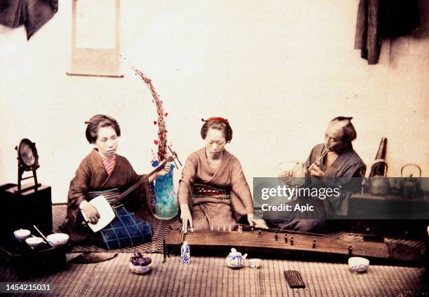 Japanese women playing Musical Instruments in presence of a man listening to them, Hand-tinted albumen photograph by Beato, c1860s..