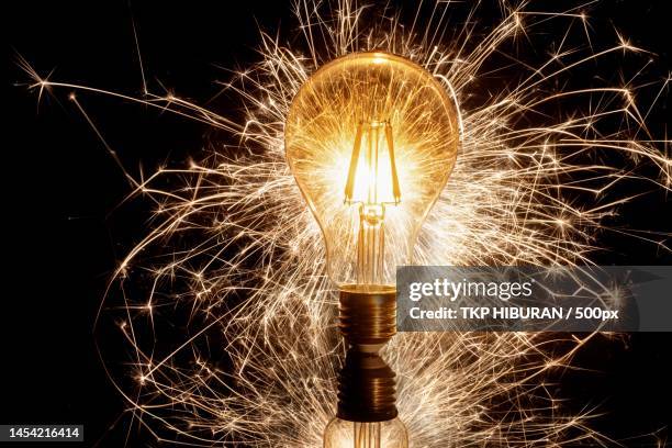 close-up of illuminated light bulb against black background,indonesia - genio concetto foto e immagini stock