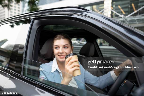 businesswoman dringking cofee while driving - wegwerpbeker stockfoto's en -beelden