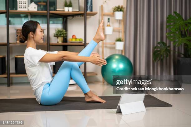 young asian woman doing online yoga class with laptop in the living room at home in the morning - yoga ball work 個照片及圖片檔