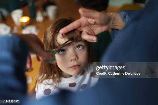 a mom is cutting her daughter's hair - réalisme photos et images de collection