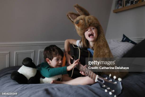a 7 year old girl, dressed as a rabbit, playing guitar in her bedroom with her brother - real life funny stock pictures, royalty-free photos & images