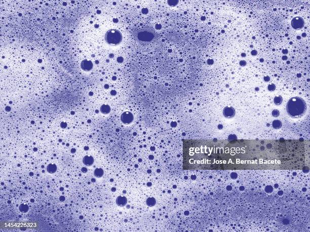 full frame of the bubbles and soap suds in the bathroom on a lilac background. - soap land fotografías e imágenes de stock