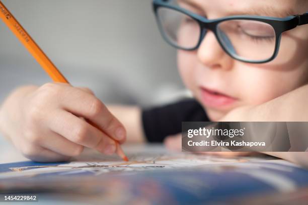 a boy of 8 years old in glasses draws with a colored pencil at the table at home, close up - color pencil stock pictures, royalty-free photos & images