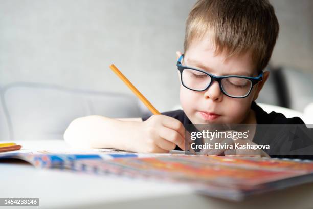 a boy of 8 years old in glasses draws with a colored pencil at the table at home, close up - 8 9 years imagens e fotografias de stock