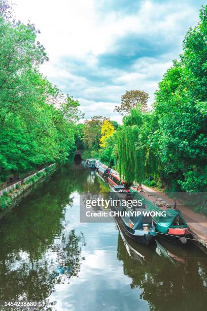 segeln auf der themse in little venice, london, mit bunten lastkähnen unter den bäumen an den seiten - grand union kanal stock-fotos und bilder