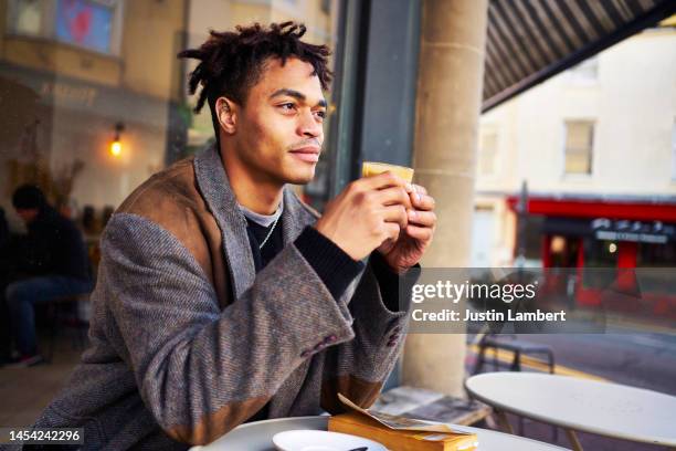 fashionable young man contemplating over a cup of coffee outside a cafe - masculine stock pictures, royalty-free photos & images