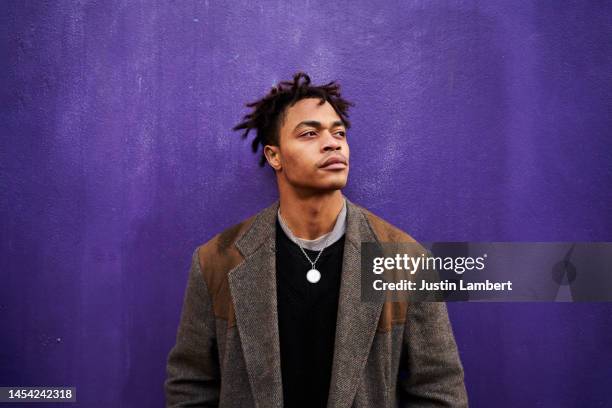 portrait of a man looking away shot against a purple backdrop - portrait coloured background stock pictures, royalty-free photos & images