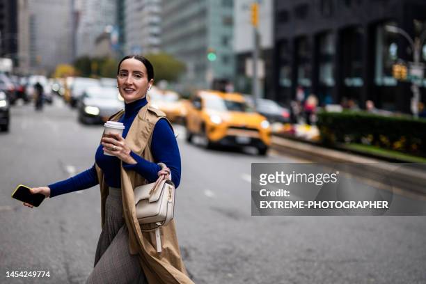 a businesswoman seen crossing the street in new york during a busy work day - businesswoman nyc stock pictures, royalty-free photos & images