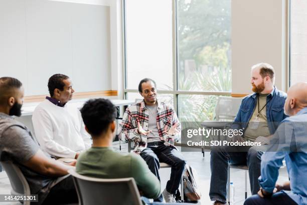 verschiedene männer hören jungen männern zu, die an einem therapietreffen teilnehmen - group therapy stock-fotos und bilder