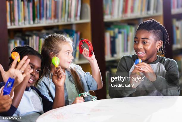 children make music with toy instruments in school library - maracas stockfoto's en -beelden