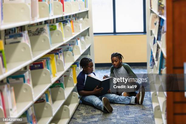 two african-american boys reading on library floor - boy library stock pictures, royalty-free photos & images