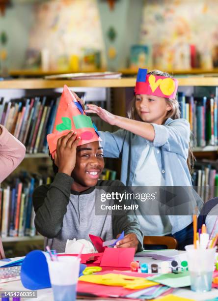 niños haciendo manualidades, haciendo sombreros de papel - papel para manualidades fotografías e imágenes de stock