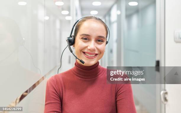 front view of woman smiling at camera while wearing headset in the office. woman in casual dress while working in call center. - camera operator imagens e fotografias de stock